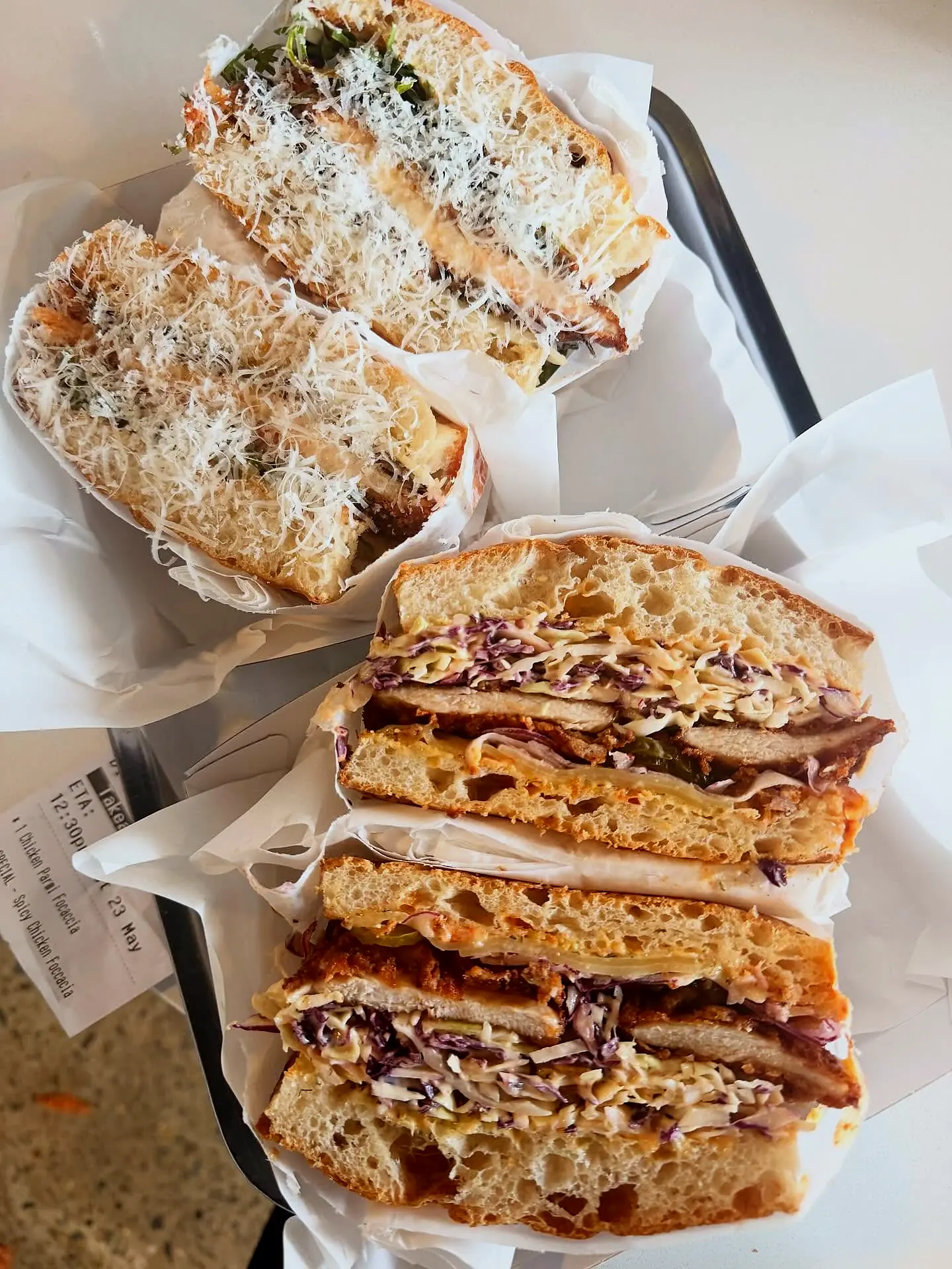 Their focaccias cut open and stacked in white paper on a steel tray